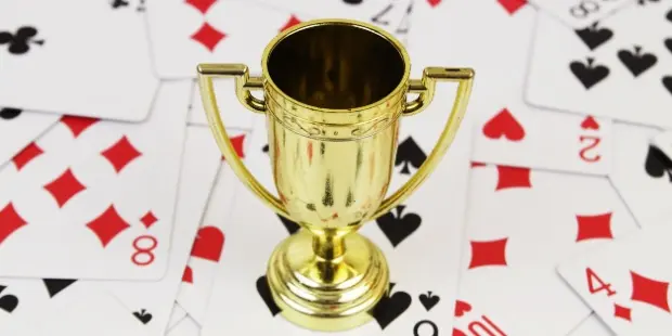 a championship cup sitting on cards strewn all over the table.