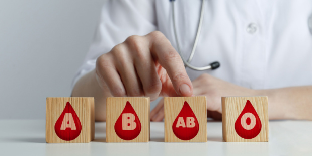A doctor pointing out different blood types printed on wooden cubes. 