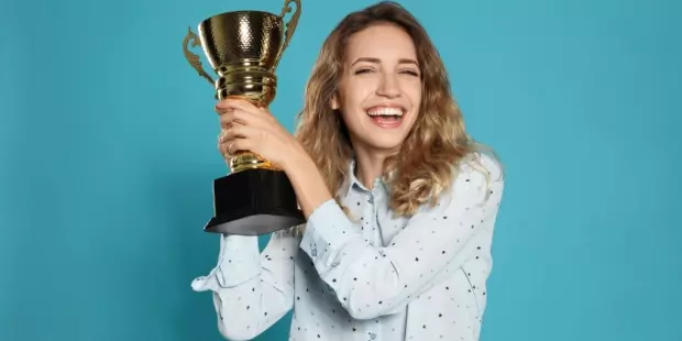 Woman happily holding a winner's cup