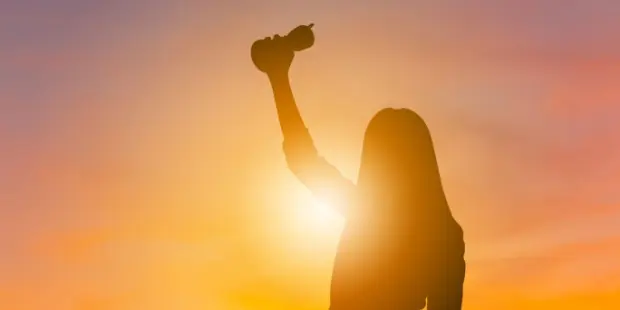 A silhouette of a woman holding a trophy. 