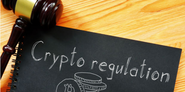 Crypto Regulation written on the front of a notebook with a gavel near it. 
