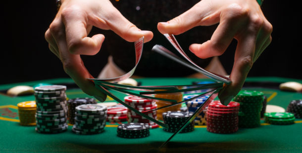 poker dealer shuffling the cards at a poker table with chips