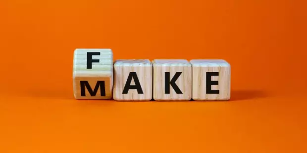 The words fake and make spelled out on wooden cubes. 