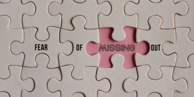 A puzzle board missing one piece, with the next words printed on it: fear of missing out. 