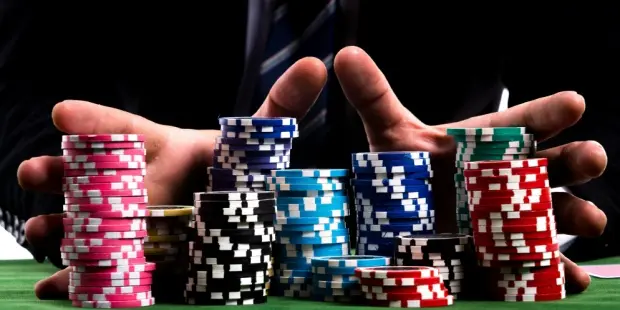 A man pushing all his poker chips as he goes all-in while playing poker.