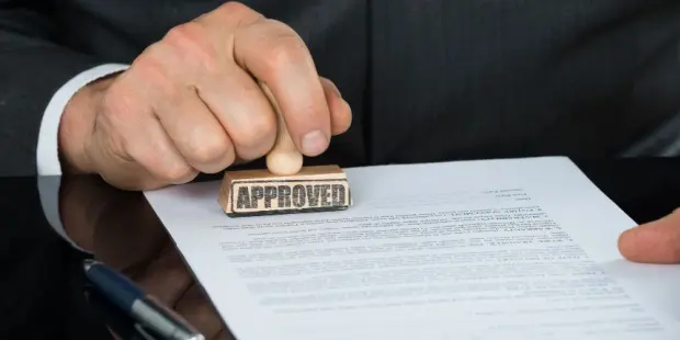 A businessman approving and stamping a contract at his desk. 