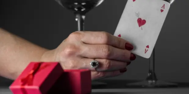 A woman holding a card with wine glasses and a gift box in the background.