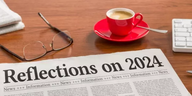 A newspaper article titled "Reflections on 2024" lying on a wooden table. 