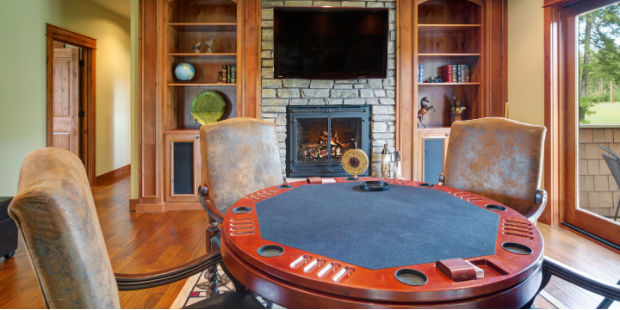 A poker table surrounded by empty chairs in a cozy room. 