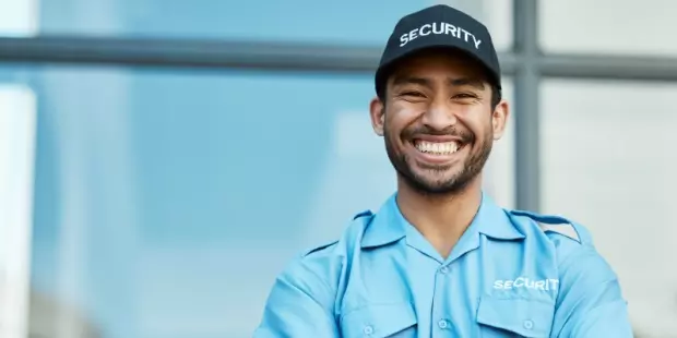 Security guard standing with his arms folded with a big smile.