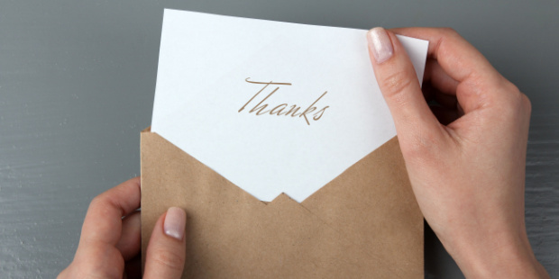 A woman pulling out a thank you note out of an envelope. 