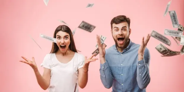 A man and a woman celebrating their wins with cash raining down on them.