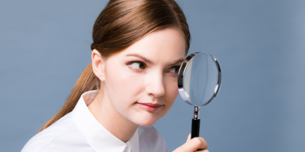 A woman looking through a magnifying glass.