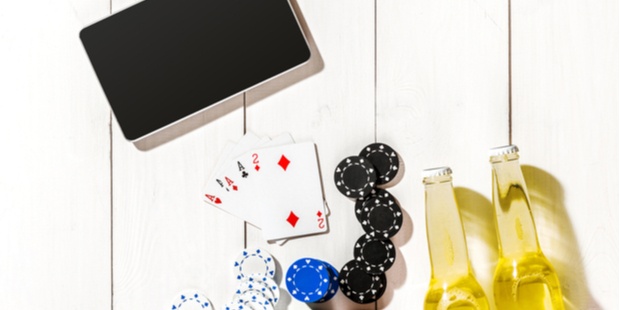 beer, poker chips, cards and tablet on a table