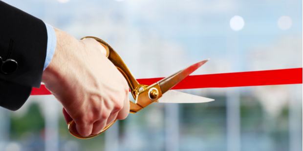 business man cutting a red ribbon