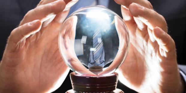  businessman trying to touch a crystal ball lying on a wooden table