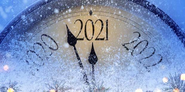 a clock turning 2021 with snow all around and evergreen boughs at the bottom