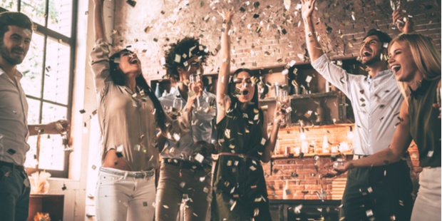 A group of people throwing confetti and having a party. 