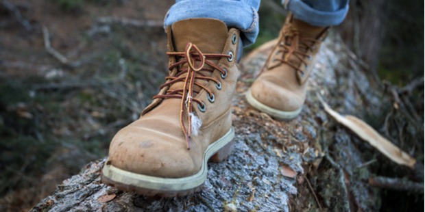 close-up of someone's hiking boots walking on a log