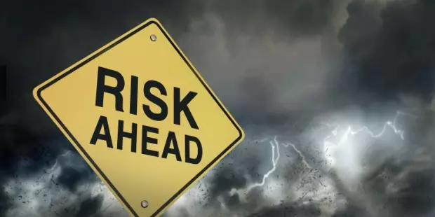 A sign reading 'risk ahead' with a stormy sky in the background.