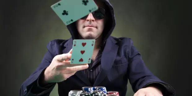 A poker player throws two weak cards at the table.