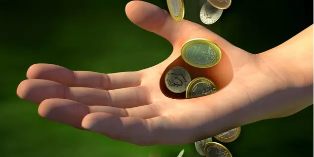 Coins passing through a hole in a man's hand