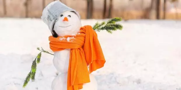 funny snowman with an orange scarf and a bucket on its head