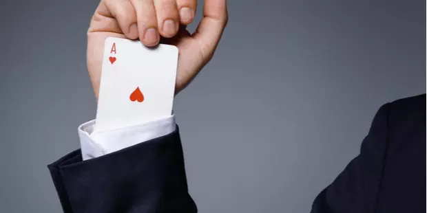 man hiding an ace up his suit's sleeve