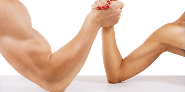 A photo of a man arm wrestling against a woman. 