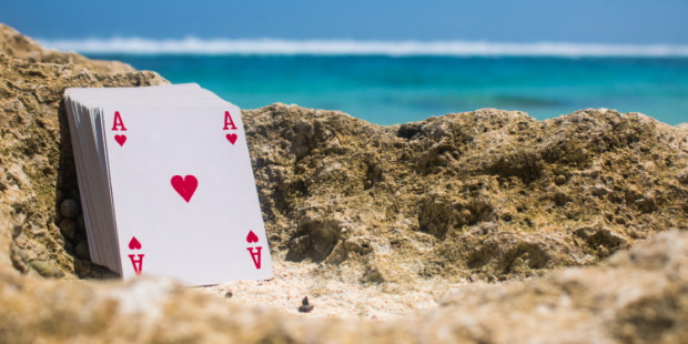 A deck of cards lying on a sandy beach.