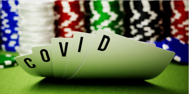 A pack of cards spelling out the word "COVID", appearing on the background of poker chips. 