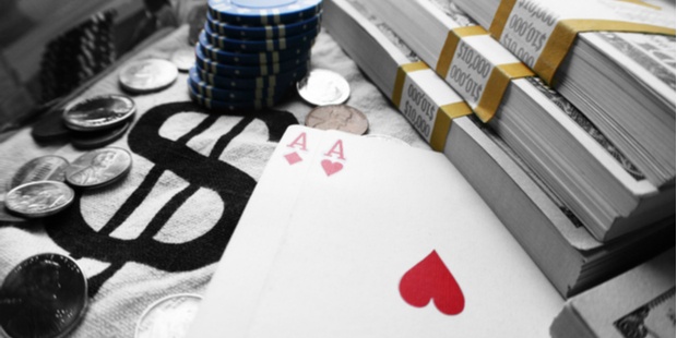 A pair of aces, appearing near a stack of cash and poker chips. 