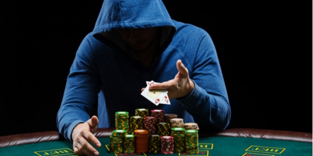 hooded poker player sitting at a poker table