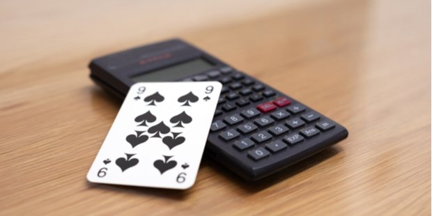A picture of a playing card positioned on top of a calculator.
