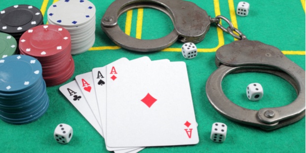 Poker chips, four aces, and police handcuffs lying on a poker table.
