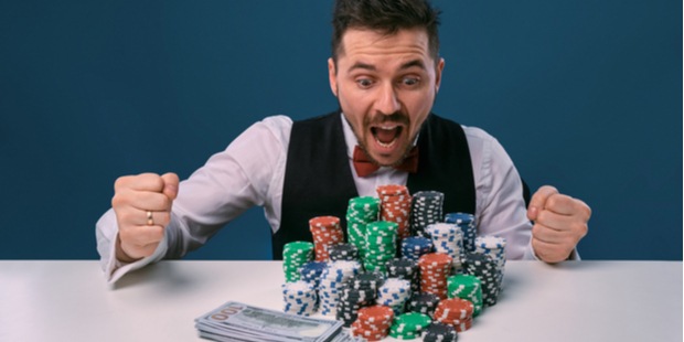 a poker player excited with a pile of chips and cash in front of him.