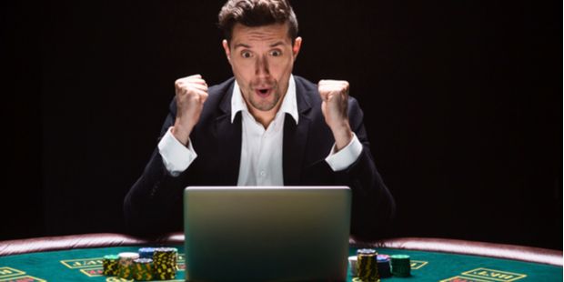 an online poker player with his laptop sitting at a real poker table