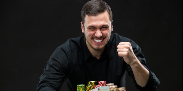photo of a poker player holding two aces and raking in a pile of chips