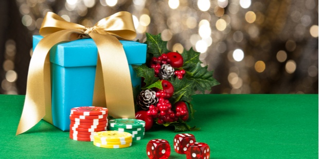 Poker chips, red dice, a present package, and Christmas decorations on a poker table. 