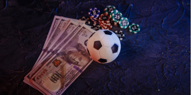 soccer ball lying next to poker chips and a stack of cash. 