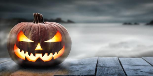 A spooky Halloween pumpkin appears on a misty gray background. 