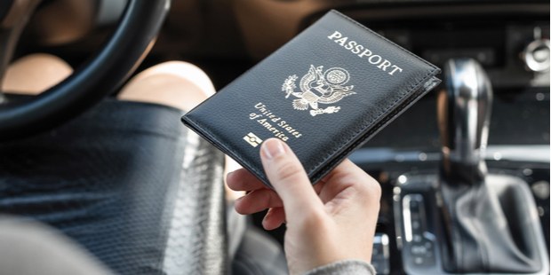 A woman sitting in a car, holding a passport. 