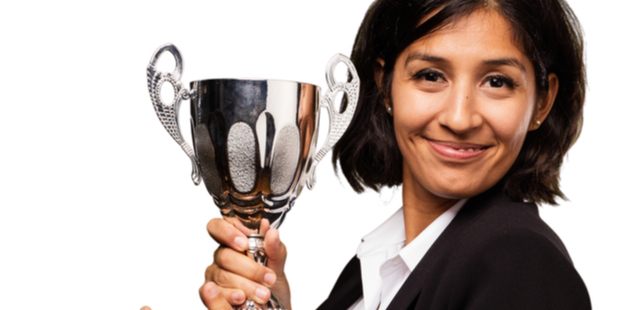 woman in a suit smiling holding a trophy